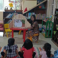 A storyteller uses a Kamishibai box to tell a story about birds. The sliding panels create a sense of anticipation as each new scene is revealed.