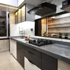 A modern kitchen design featuring a serving window that opens into the dining area. The kitchen has dual-tone cabinets, a grey quartz countertop, and textured glass overhead units with internal lighting.