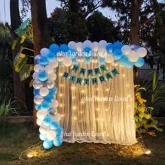 A simple and elegant balloon arch with a fairy light curtain, set up outdoors in a garden. This is perfect for an evening celebration.