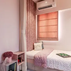 A wider view of the compact pink room, showing the daybed setup with a custom headboard and roman blinds. The use of a curtain can partition the sleeping area, creating a cozy nook that feels private and secure.