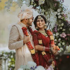 A beautiful candid moment of the couple sharing a laugh during their jaimala ceremony under a floral arch.