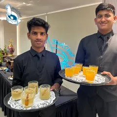 Our servers presenting trays of refreshing welcome drinks, including a spiced apple cooler and a vibrant orange beverage.