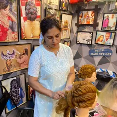 A student deeply focused on creating an intricate braid on a mannequin. This is where the real learning happens, with dedicated practice and attention to detail.