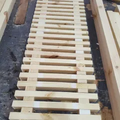 The assembly process begins. The slatted top of the bench is being glued and clamped, using spacers to ensure uniform gaps between each piece of wood.