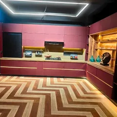 We love it when clients are not afraid to use color. This L-shaped modular kitchen showcases a bold and beautiful magenta finish, perfectly balanced with natural wood open shelving. The chevron-patterned flooring and integrated LED lighting in the cabinetry create a space that is vibrant, modern, and full of personality.