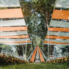We used flowing drapes in orange and white to create a beautiful overhead canopy, leading the eye towards a simple and elegant teepee-style mandap for this outdoor wedding.