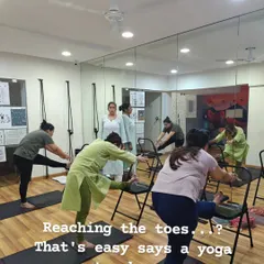 Reaching your toes is not the goal; moving with awareness is. I use props like chairs to make poses like the forward bend accessible to everyone. This ensures you can work on spinal alignment and hamstring flexibility safely, no matter your starting point.