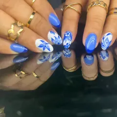 A beautiful and intricate blue and white floral design, reminiscent of classic porcelain, on almond-shaped nails.