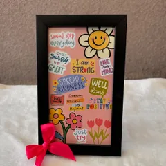 A frame designed to inspire self-love and positivity. This piece is filled with cheerful stickers and motivational quotes like "Spread Kindness" and "Stay Positive," tied with a bright pink bow.