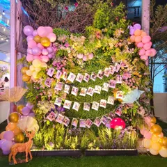A creative photo wall I designed using a lush backdrop of greenery, flowers, and balloons. I hung strings of the couple's polaroid photos for guests to see.