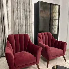 A pair of elegant armchairs in a deep burgundy velvet. The channel-tufted back and tapered wooden legs create a look that is both modern and timeless, perfect for adding a touch of sophisticated color.