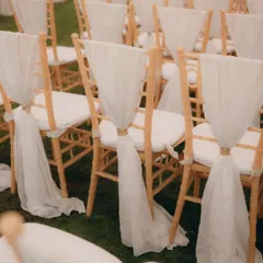 The elegant seating arrangement for the ceremony, with flowing white drapes on the chairs, waiting for guests to arrive.