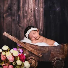 This peaceful newborn portrait highlights the tiny, delicate features of the baby. I use props like this rustic cart and soft flowers to add a touch of warmth.