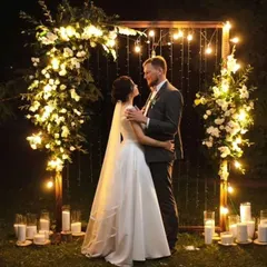 A simple and romantic photo backdrop for a couple. The wooden frame is decorated with white flowers and fairy lights, creating a magical setting for pictures at an evening event.