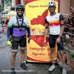 Two of our riders stand proudly before the Bangalore Randonneurs banner after completing the Rajyotsava 200k brevet. The Strava data overlay shows their impressive time and distance for the day's ride.