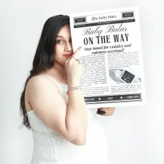 A playful peek from behind the "Baby On The Way" newspaper prop. This is a creative and memorable way to capture your excitement for the big news.