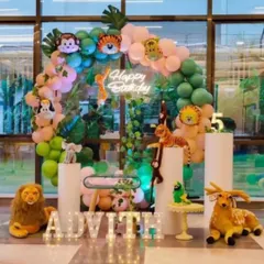 A fun jungle animal theme with many plush toys and cutouts. This setup includes a balloon arch with animal head foils, a 'Happy Birthday' neon sign, and light-up letters, creating an immersive jungle experience.