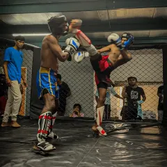 Our training is relentless because the fight demands it. Here, one of our fighters executes a powerful high kick during an in-house kickboxing tournament, a testament to the striking skills we build.