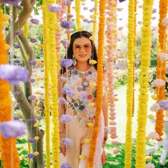 A guest poses within a curtain of colorful marigold and carnation garlands. This interactive floral installation provided a perfect photo opportunity and added a playful, textural element to the bachelorette party decor.