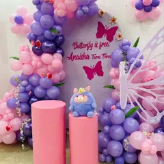 A close-up shot of the custom backdrop and balloon arch for the "Butterfly is free, Anaisha Turns Three" party. You can see the small details like leaves and smaller butterflies within the arch.