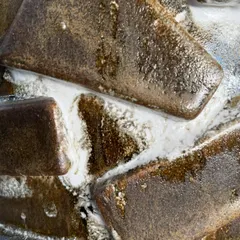 An extreme close-up of two different glazes interacting on a test piece. The way the brown and white glazes melt and push against each other creates a fascinating, organic pattern.