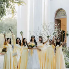 The bride and her joyful bridesmaids in their beautiful yellow dresses, celebrating together outside a classic Chennai church.