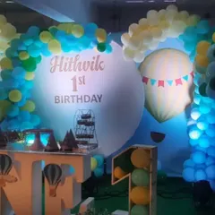 A "Hot Air Balloon" adventure theme for Hithvik's first birthday. The design features a custom circular backdrop, large "ONE" props with hot air balloon details, and blue, yellow, and green balloons.