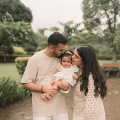 A beautiful, tender moment as both parents kiss their baby's cheeks. The soft outdoor light makes it even more special.