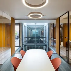 This meeting room at the Laxcon office is designed with full-height glass walls overlooking the central atrium, promoting a culture of transparency and connection.