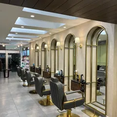 For the Madonna Salon in New Delhi, we designed a serene and elegant styling area. The repeating brass-framed arched mirrors and custom lighting create a rhythmic and sophisticated atmosphere, ensuring clients feel pampered and relaxed.