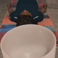 The placement of the bowls can enhance the experience. Here, a large crystal bowl is positioned near a participant's head to maximize the soothing effect of its vibrations on the mind.