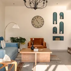 This living room was designed for a single doctor, reflecting her vibrant personality. I balanced a calming blue sofa with a rich, rust-colored armchair and created visual interest with a series of deep teal arched niches for displaying personal treasures.