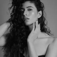 A classic black and white portrait that celebrates voluminous, curly hair. The makeup is kept soft and glowing to let the natural texture and beauty of the hair shine.