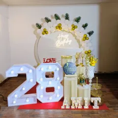 A beautiful white and gold themed 28th birthday. The setup includes large marquee numbers, a 'Happy Birthday' neon sign, and elegant plinths.