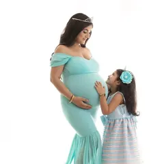 A sweet maternity photo with an older daughter looking up at her mother's baby bump. Including siblings in the shoot is a wonderful way to capture the family's excitement.
