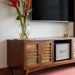 The TV console at the Layam residence was designed to house a specific sound system. The shutters feature brass sheets and wooden details resembling a Mridangam, fitting for a home centered around music.