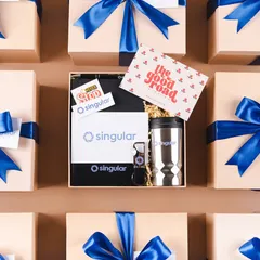 We love seeing our workshop filled with beautifully branded boxes ready for dispatch. This flat lay shows a batch of custom welcome kits for our client Singular, each packed with care and tied with their signature blue ribbon, ensuring a consistent and professional brand experience.