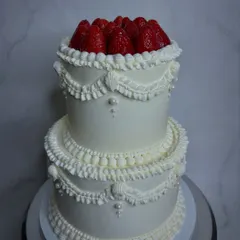 A modern take on old-world charm for a contemporary bride. This two-tiered cake features intricate Lambeth piping and is crowned with fresh, juicy strawberries for a beautiful and delicious statement piece.