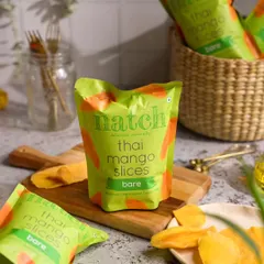 Product photography for Natch Snacks, styling their Thai Mango Slices in a natural, light-filled setting to emphasize the snack's wholesome appeal.