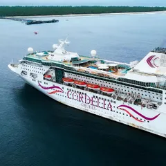 The Cordelia cruise ship anchored off the coast of an island, captured from a drone. This shot is ideal for cruise line marketing, showing the ship as a gateway to paradise.