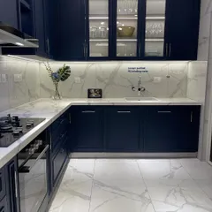 This modern kitchen features sleek navy cabinetry, marble patterned surfaces, and integrated lighting. It's a perfect example of the curated, high end interiors I look for in a property.