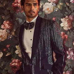 We redefine formal wear with this modern tuxedo, featuring a shawl lapel embellished with a cascade of kut-dana work for a touch of sophisticated glamour.