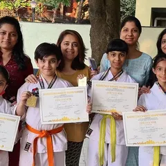 Proud mothers stand with their children, our tournament winners from the Purva Belmont dojo. Success in karate is a community effort.