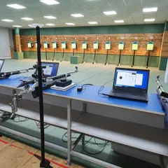 A view of the firing line prepared for a competition. Each lane is equipped with a laptop connected to an electronic target system for precise, real time scoring.