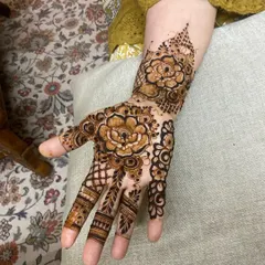 A bold Arabic design centered around large, shaded flowers on the back of the hand.