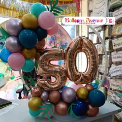 A compact tabletop balloon arrangement for a 50th birthday, featuring a small ring frame and rose gold number balloons.