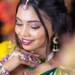 A close-up of a Haldi look, focusing on the beautiful magenta lip color that contrasts with the yellow and green outfit. The floral maang tikka adds a perfect touch.