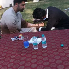 Our tattoo artist is seen here working at an outdoor corporate event, providing a fun and relaxing activity for employees.