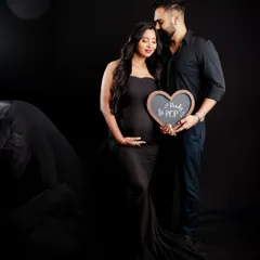 "Ready to POP!" This couple's portrait uses a cute heart-shaped sign to add a playful touch to their dramatic, dark-background maternity shoot.