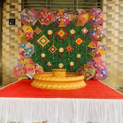 This Haldi setup features a traditional urli at the center, set against a backdrop of a green wall decorated with colorful Rajasthani umbrellas and dreamcatchers. It’s a perfect photo spot for a fun-filled ceremony.